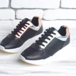 DALL·E 2024-06-07 09.09.16 - A pair of stylish urban women's sneakers. The shoes should be modern with a fashionable design, primarily in black, accented with metallic or pastel d